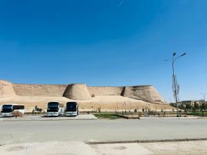 two buses parked in a parking lot in front of a building at Guest House Bekturdi in Khiva