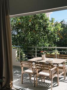 a wooden table and chairs on a balcony with an orange tree at Tashó Simply Living in Xylokastro
