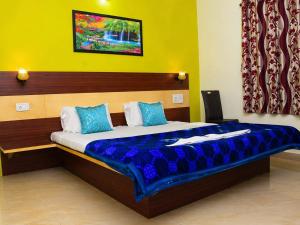 a bedroom with a large bed with blue pillows at Hotel Matheran Gaurav Cottage in Matheran