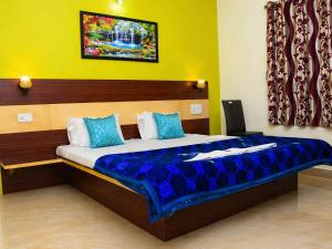 a bedroom with a large bed with blue pillows at Hotel Matheran Gaurav Cottage in Matheran