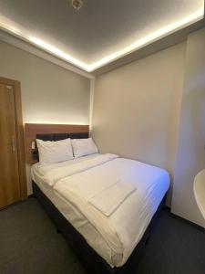 a bedroom with a bed with white sheets and a sink at Hotel Bergama in Istanbul