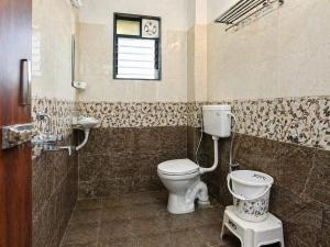 a bathroom with a toilet and a window at Hotel Matheran Gaurav Cottage in Matheran