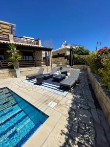 a pool with chairs and an umbrella next to a house at Villa Balmoral in Peyia