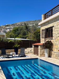 a swimming pool with two chairs and a house at Villa Balmoral in Peyia