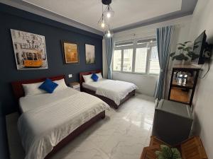 a bedroom with two beds and a blue wall at Khách Sạn Cây Xanh in Da Lat