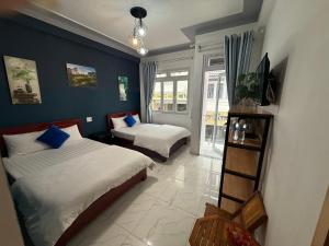 a bedroom with two beds with blue walls at Khách Sạn Cây Xanh in Da Lat