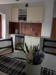 a kitchen with a table with a vase of flowers on it at Mirni krov in Dražice