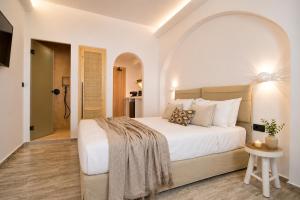 a bedroom with a large white bed and a table at Aegeeis in Perissa +64 photos