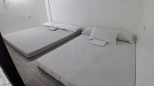 a white bedroom with two beds in it at Starksway Resort in Calubcub Primero