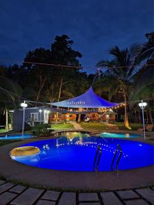 a resort with a blue pool at night at Starksway Resort in Calubcub Primero
