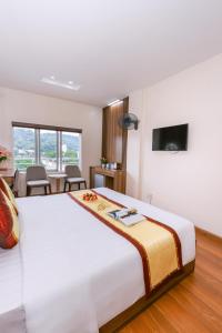 a bedroom with a large white bed and a table at Kim Long Hotel Lao Cai - Near Hekou Border Gate in Lao Cai