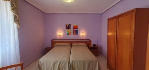 a bedroom with a bed with purple walls at Hostal Restaurante Carolina in Pedrosillo el Ralo