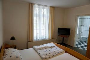 a bedroom with a bed and a television and a bathroom at Hotel zum Freiheiter Hof in Raesfeld