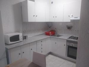 a kitchen with white cabinets and a microwave at Siroco Nau Algarve in Olhão