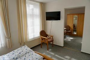 a bedroom with a bed and a tv and a chair at Hotel zum Freiheiter Hof in Raesfeld