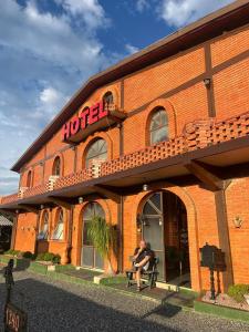 Ein Mann sitzt auf einer Bank vor einem Hotel in der Unterkunft Hotel Blumenpark in Rio Negro