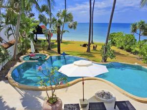 a swimming pool with an umbrella and the ocean at Beachfront! 5 Bedrooms - Malee Beach Villa E1 in Ko Lanta