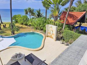 a swimming pool with a view of the ocean at Beachfront! 5 Bedrooms - Malee Beach Villa E1 in Ko Lanta