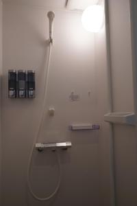 a shower in a bathroom with a hose on the wall at Guest House Hasegawa in Sakaki