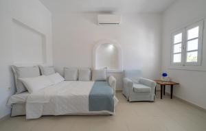 a white bedroom with a bed and a chair at Coastal Escape - 2 min from Perissa Beach in Perissa