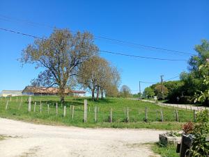 a field with a fence and trees on a hill at Au jeu de mots, chambre d'hôtes proche Poligny in Barretaine