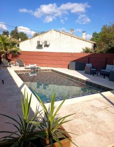 a swimming pool with chairs and a building at LA LIBELLULE de PROVENCE in Morières-lès-Avignon