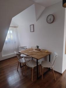 a dining room table with chairs and a clock on the wall at Ostoja Jaczno in Smolniki +15 photos