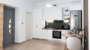 a kitchen with white cabinets and a table and a stove at Liopetro in Sitia