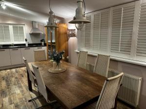 a kitchen with a wooden table with chairs and a kitchen with white cabinets at Bungalow Nathalie in Julianadorp