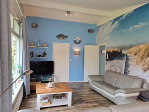 a living room with a couch and a blue wall at Bungalow Nathalie in Julianadorp +16 photos