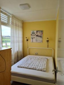 a bedroom with a bed with a yellow wall at Bungalow Nathalie in Julianadorp