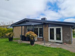 a brick house with a door and a yard at Bungalow Nathalie in Julianadorp