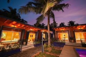 a house with a palm tree in front of it at Oyster Bay Beach Resort in Anjuna