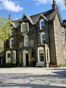 an old brick house with a bench in front of it at The Grasmere Hotel in Grasmere