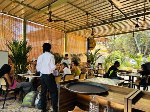 a group of people sitting at tables in a restaurant at Oyster Bay Beach Resort in Anjuna