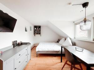 a white bedroom with a bed and a table at SkyNest Pirna gemütliches Dachstudio mit Stadtblick in Pirna