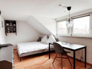 a bedroom with a bed and a desk and a window at SkyNest Pirna gemütliches Dachstudio mit Stadtblick in Pirna