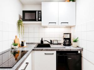 a white kitchen with a sink and a microwave at SkyNest Pirna gemütliches Dachstudio mit Stadtblick in Pirna