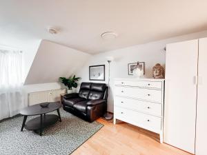 a living room with a leather chair and a dresser at SkyNest Pirna gemütliches Dachstudio mit Stadtblick in Pirna