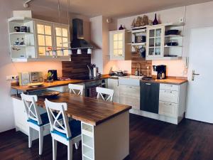a kitchen with a wooden table and white cabinets at Ocean View Laboe in Laboe
