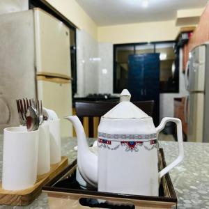 a tea kettle and cups on a tray on a kitchen counter at StayLuxe Rooms & Apartments Near BKC, Chembur in Mumbai