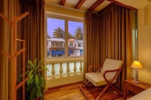 a room with a window with a chair and a window with a view at Cairo in Siolim
