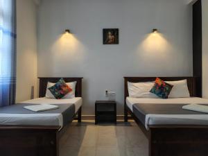 two beds in a room with two tables at Lake Edge Resort in Anuradhapura