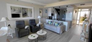 a living room with two chairs and a couch at Dolphin Beach H203 Table Mountain Views in Bloubergstrand