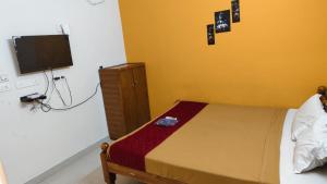 a bedroom with a bed and a flat screen tv at Priyan Beach View Residency in Kuilapayam