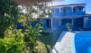 a blue house with a swimming pool in front of it at Espaço Sol in Peruíbe