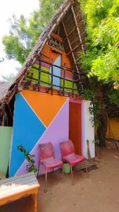 two chairs and a house with a colorful wall at Priyan Beach View Residency in Kuilapayam