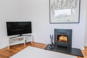 a living room with a fireplace and a flat screen tv at Bod A Quinte in St Ives