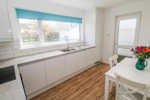 a kitchen with white cabinets and a window at Bod A Quinte in St Ives