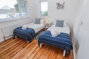 two beds in a room with wooden floors and a window at Bod A Quinte in St Ives